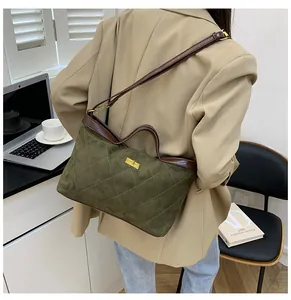 Close-up of green suede shoulder bag with brown leather strap and gold clasp detail