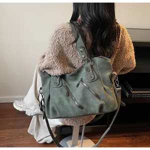 Détail du sac cabas vintage vert foncé avec rivets métalliques et zips décoratifs sur le côté