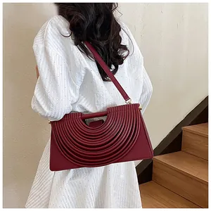 Close-up of burgundy woven shoulder bag featuring unique pleated geometric pattern on the back
