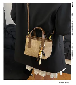 Detailed view of a retro bucket bag featuring canvas, leather trim, and beaded charm