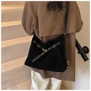 Detail of black suede tote bag featuring crisscross leather straps and gold buckle
