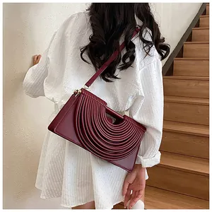 Close-up of deep red woven crossbody bag with unique semi-circle pleated design detail
