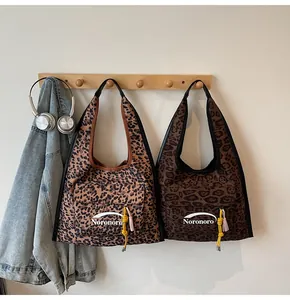 Close-up of leopard print canvas hobo bag with front pocket and yellow tassel detail