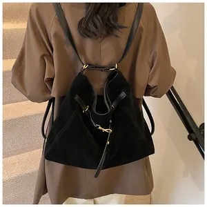 Detail of the black suede backpack with gold hardware worn over a brown winter coat