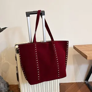 Λεπτομέρεια μπορντό σουέτ τσάντα με ασημένια τρουκς πάνω σε λευκή βαλίτσα ταξιδιού