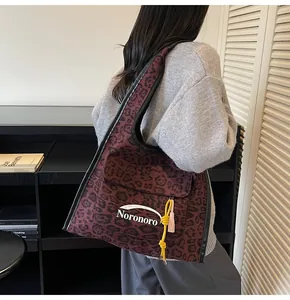 Detail showing red leopard print tote bag with yellow tassel and logo on a model