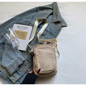 Nahaufnahme der beige wasserdichte Nylon Sporttasche mit Gurt auf einer Denim Jacke