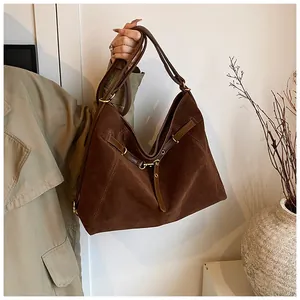 Detail of dark brown suede tote bag with leather straps and golden metal rings
