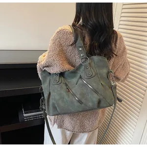 Détail d'un sac cabas vintage vert foncé avec fermetures éclair porté par un mannequin