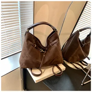 Close-up of dark brown suede tote bag with retro gold buckle and leather strap detail