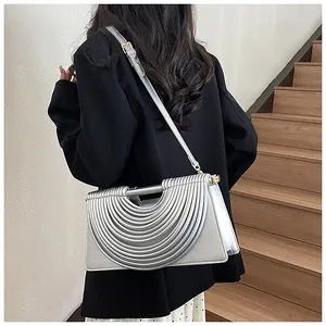 Silver woven shoulder bag with unique semicircular textured design on black suit