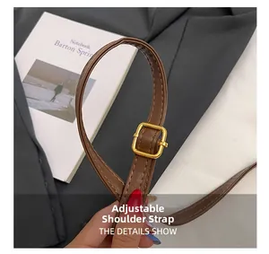 Detail of adjustable brown leather shoulder strap with a golden metal buckle