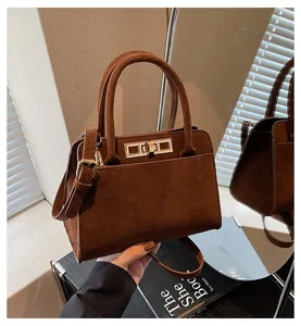 Détail du sac cabas en daim marron foncé avec fermoir doré et reflet de miroir