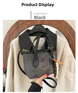 Detail of grey denim tote bag with black handles, gold hardware and colorful wood bead charm
