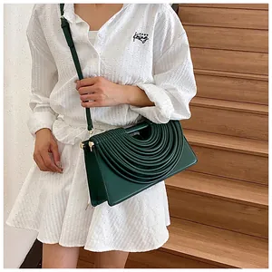 Detail view of dark green woven crossbody bag with ribbed design and golden hardware