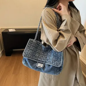 Sac bandoulière en denim bleu chic avec motif matelassé et chaîne en métal sur modèle