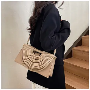 Close-up of beige woven shoulder bag featuring unique artistic pleated layers and metal parts