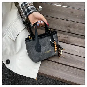 Close-up of a vintage grey canvas bucket bag with leather handles and wooden bead charm