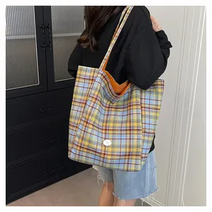 Close-up of tartan tote bag featuring orange lining and detailed plaid fabric texture