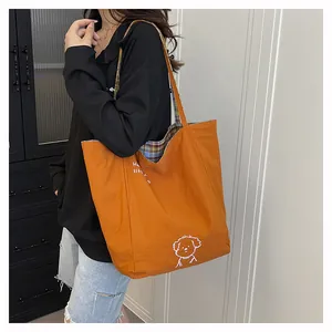 Close-up of orange tote bag showing cute dog illustration and plaid interior lining