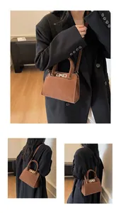 Dettaglio di una borsa tote in pelle scamosciata marrone con chiusura girevole dorata