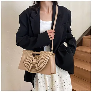 Detail view of woven shoulder bag featuring a unique half-round pleated handle and beige leather