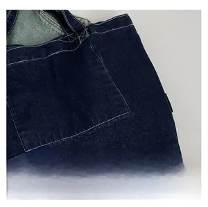 Detail of deep blue denim tote bag showing white contrast stitching and front pocket