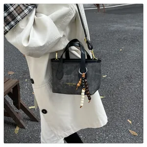 Close-up of canvas bucket bag with leather handles and decorative beaded pendant charm
