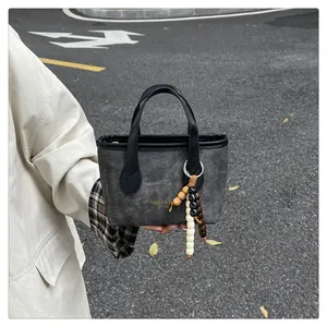 Detail of grey canvas bucket bag with black leather trim and colorful wooden beads