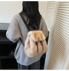 Rear view of a light brown faux fur backpack with black straps shown on a model