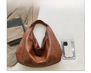 Top view of a large brown leather tote bag with metal zipper and pebbled texture