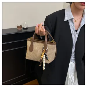 Detailed close-up of retro canvas bucket bag with wooden bead charm and leather handles