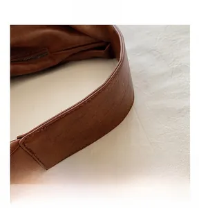 Close-up of wide leather handles and fine stitching on dark brown tote bag