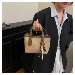 Detail of canvas handbag with brown leather handles and decorative wooden beads charm