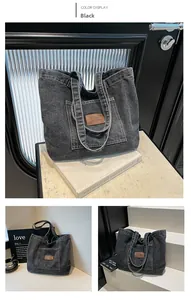 Macro detail of black washed denim tote bag with vintage brown leather brand patch