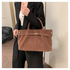 Λεπτομέρεια καφέ σουέτ τσάντας tote με διακοσμητική ασημένια αγκράφα και καρφιά