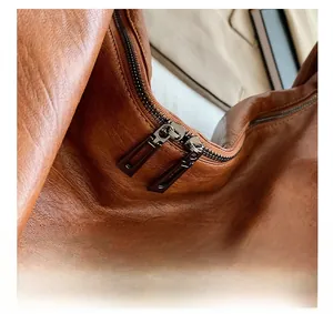 Close-up of smooth metal dual zippers on a premium brown textured faux leather tote bag