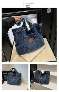 Detail of light blue washed denim tote bag with front pocket and leather logo patch