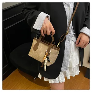 Detail of khaki suede bucket bag with wooden beads and adjustable leather shoulder strap
