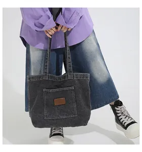 Detailed close-up of a charcoal gray washed denim tote bag with brown leather patch