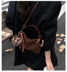 Outdoor shot of a brown suede pillow bag with leopard print pompom and tassel detail