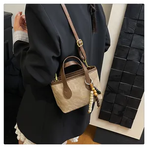 Detailed close-up of a two-tone bucket bag with adjustable strap and wooden beads