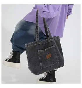 Detail of grey denim tote bag featuring a leather logo patch and woven BAILEYAO label