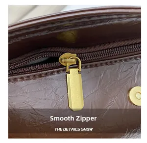 Close-up of smooth gold metal zipper on brown leather dumpling bag with fine texture
