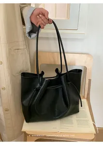 Close-up of black retro tote bag with drawstring detail and pebbled leather texture