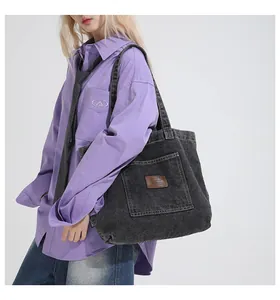 Detail view of denim tote bag with front flap pocket and leather label on shoulder strap