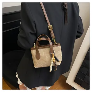 Detail of retro mini tote bag with wooden bead charm and brown leather straps