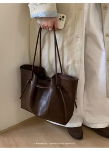 Close-up of a retro brown leather tote bag with drawstring detail and slim shoulder straps