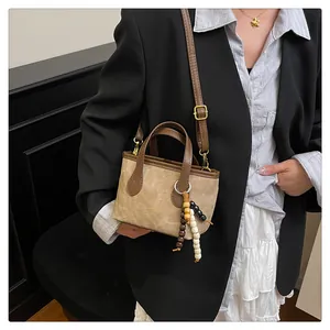 Detail of vintage suede bucket bag with leather handles and chic wooden bead charm