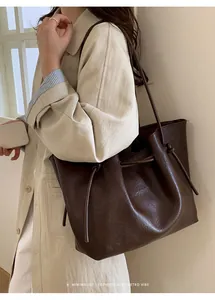Detail of dark coffee tote bag featuring adjustable drawstring knots and soft PU leather